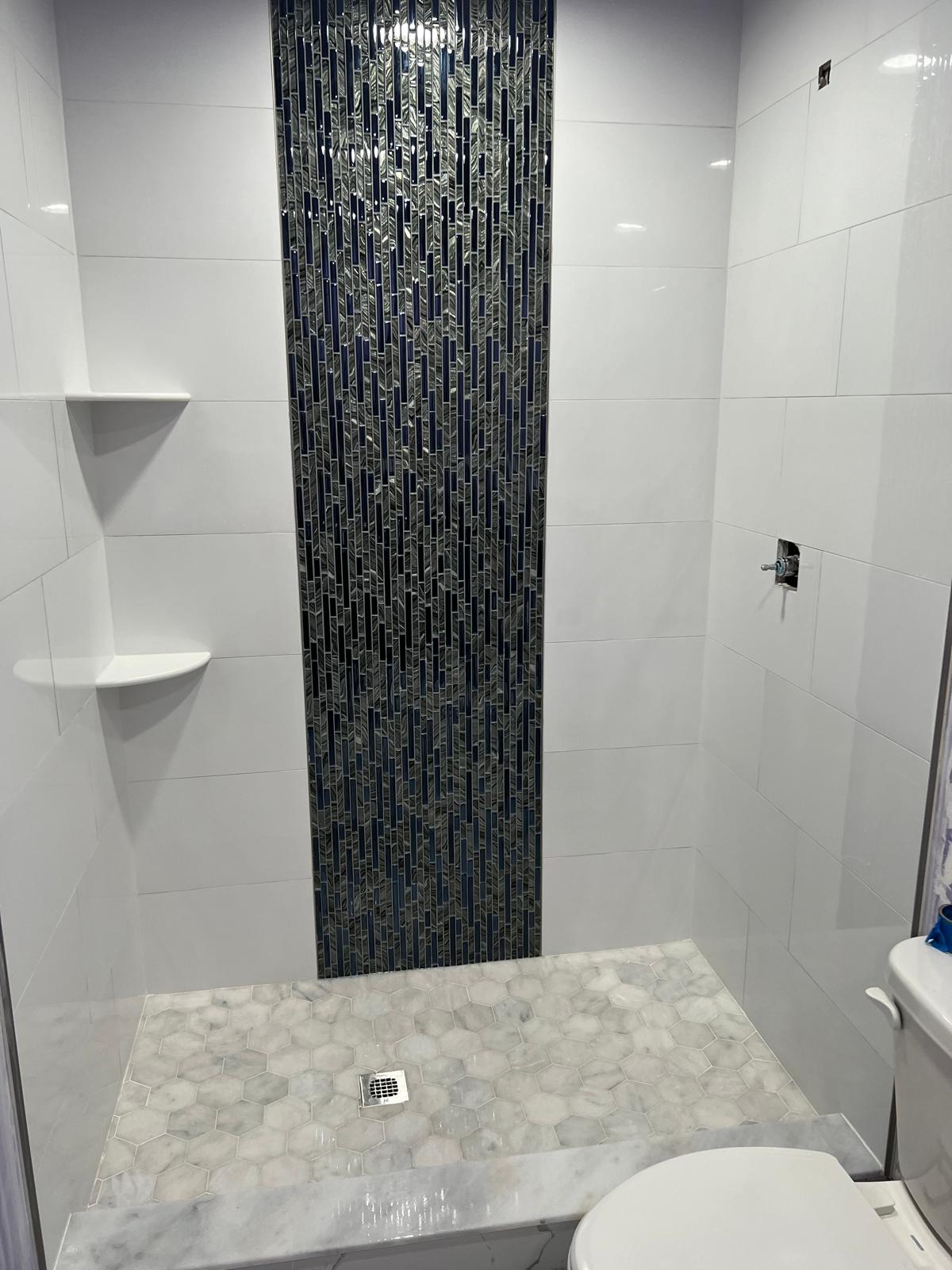 Navy and silver glass mosaic feature band running floor to ceiling in a white shower