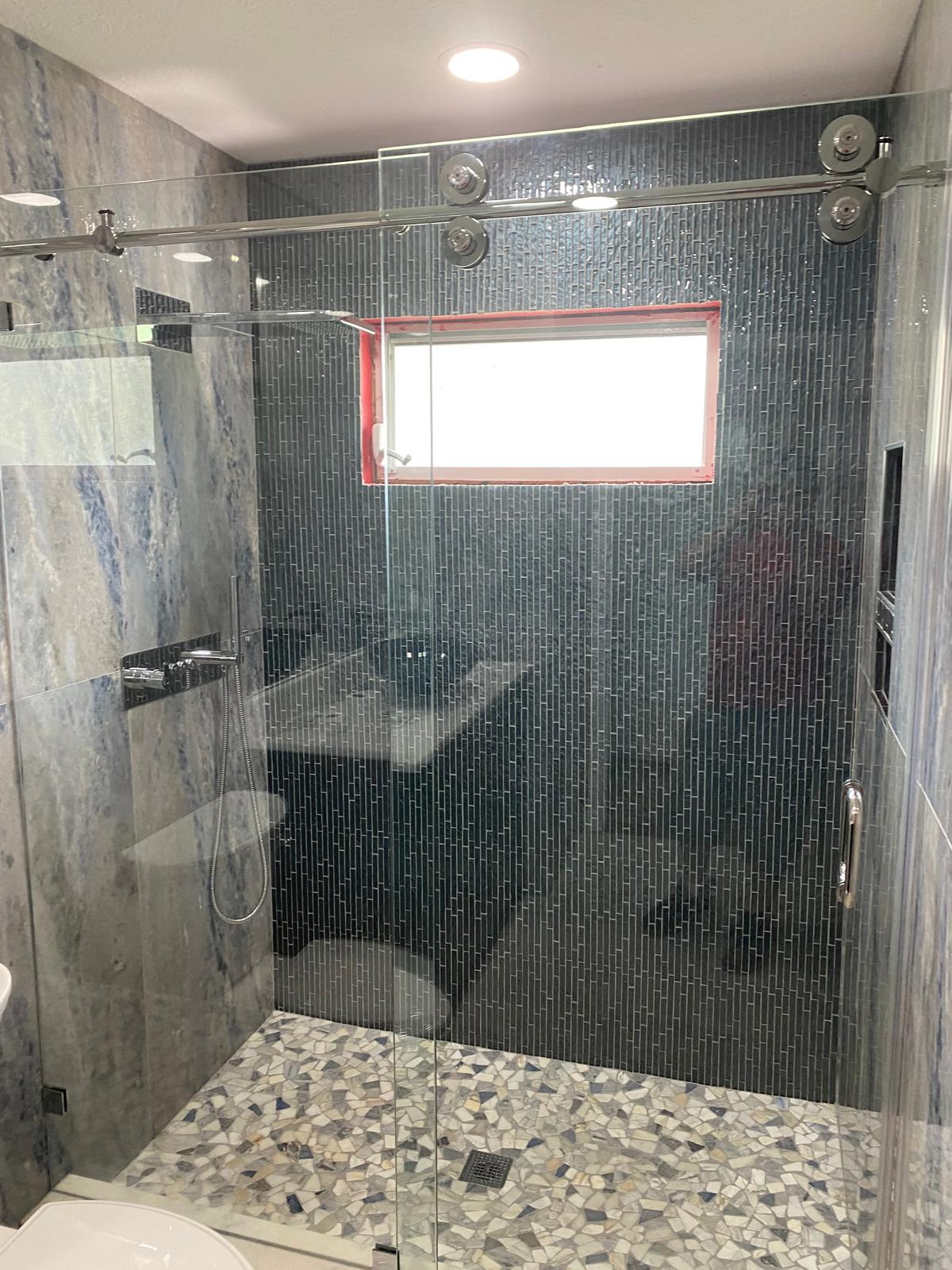 Completed Tampa bathroom remodel with blue mosaic feature wall and frameless glass door